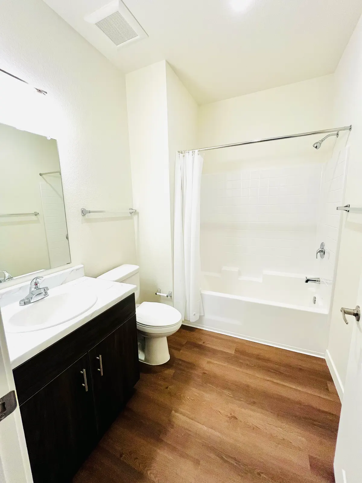 Bathroom with a vanity, toilet and bathtub behind a shower curtain.