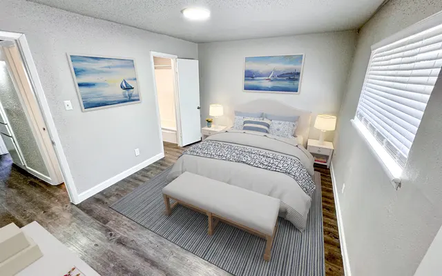 Cozy Bedroom Interior A well-decorated bedroom featuring a bed with decorative pillows, a light-colored rug, and artwork on the walls. There's a bench at the foot of the bed and soft lighting, creating a cozy atmosphere.