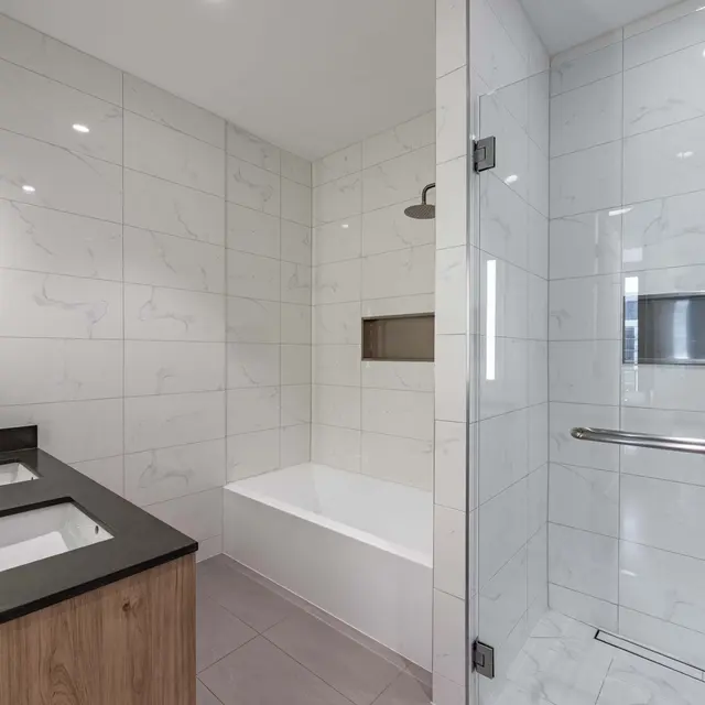 A modern bathroom featuring a freestanding tub, a glass-enclosed shower, and dual sinks with a dark countertop.