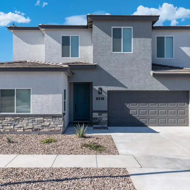 A modern two-story house with a stone and stucco exterior, featuring large windows and a two-car garage.