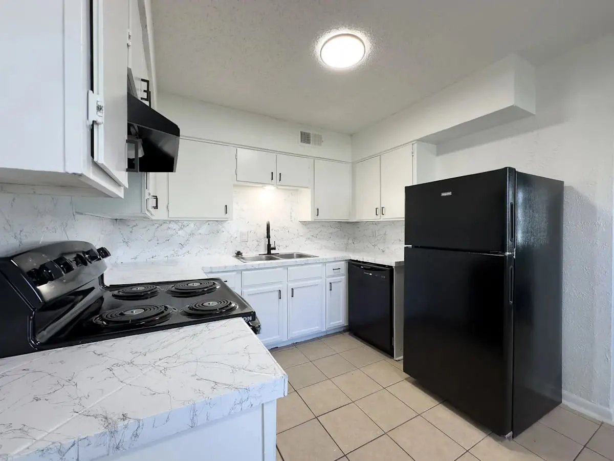 Contemporary Kitchen Design A modern kitchen featuring white cabinets, new countertops, and black appliances including a refrigerator and stove.