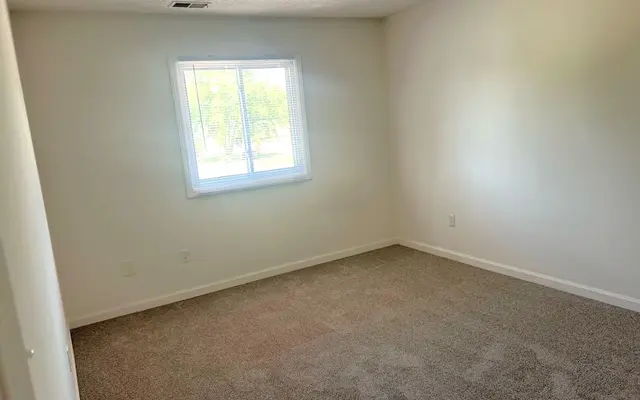 Empty Room with Natural Light An empty room with light-colored walls and a window letting in natural light.