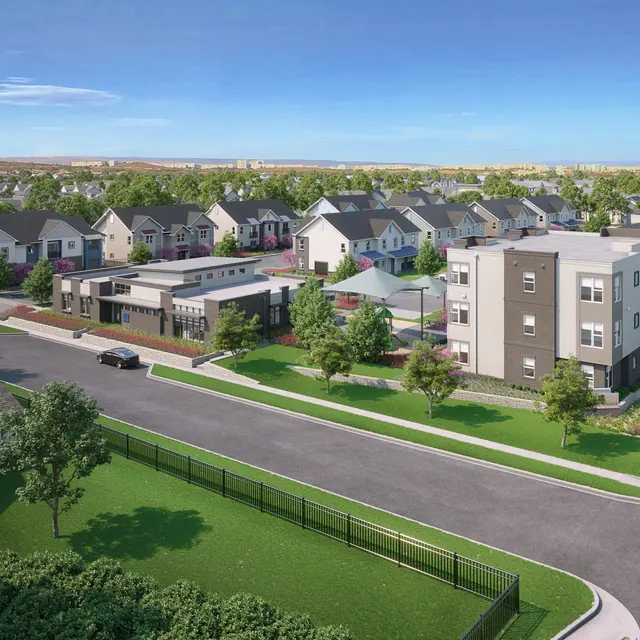 Aerial view of a modern residential community featuring single-family homes and multi-family buildings surrounded by green lawns and trees.