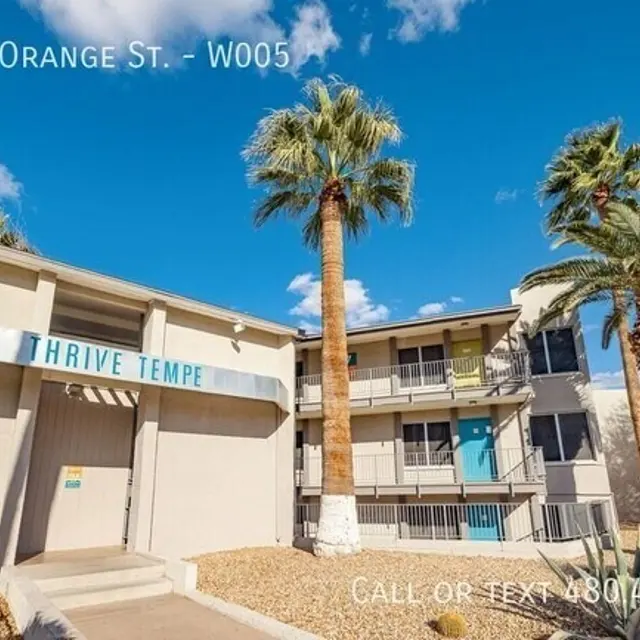 Exterior view of a multi-story residential building with palm trees, blue sky, and a sign that reads 'THRIVE TEMPE'.