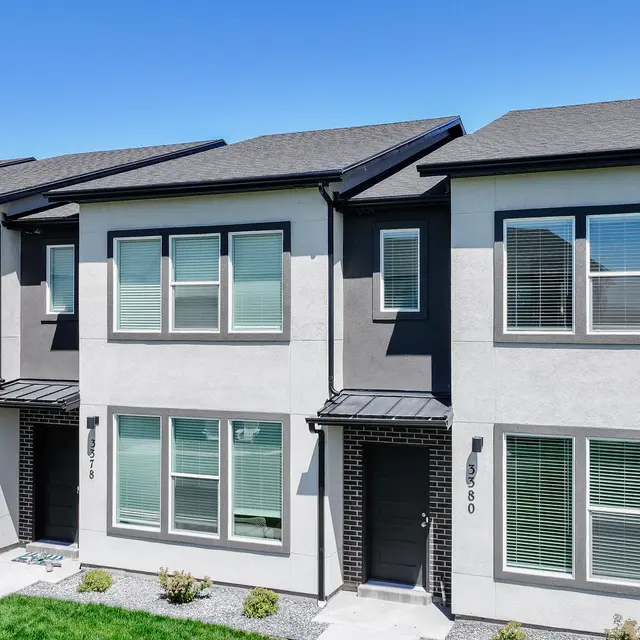 A row of modern townhouses showcasing grey exteriors with multiple windows and a landscaped front yard.