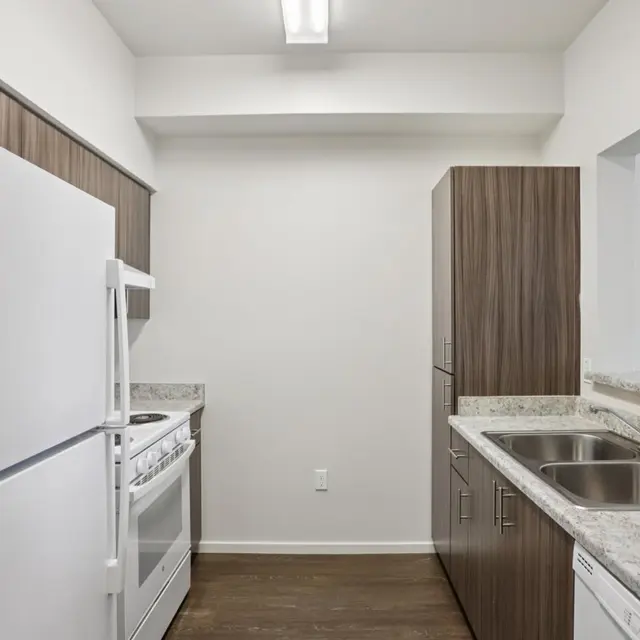 Modern Kitchen Interior A modern kitchen featuring a white refrigerator, a stove, and a dual sink with a countertop. The cabinetry is dark wood, and there is a microwave on the counter.