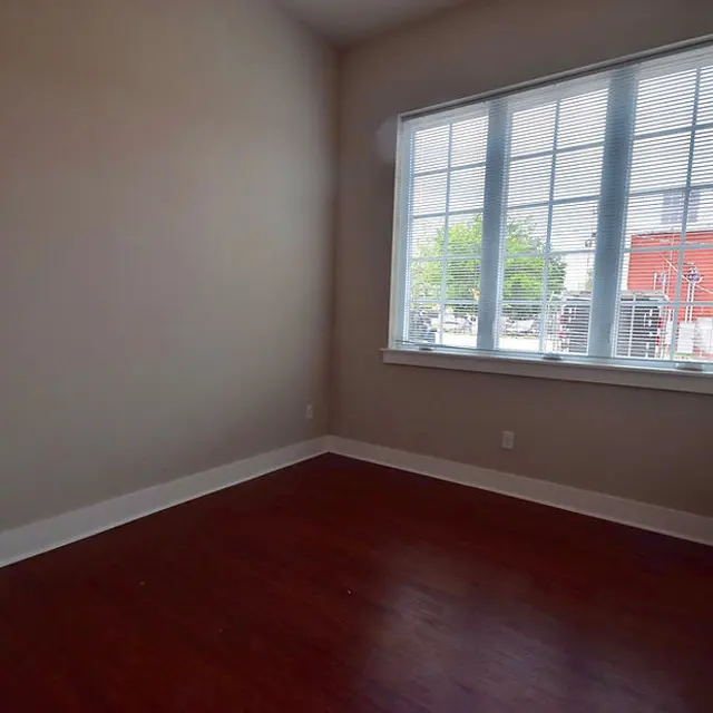 Empty Room with Window An empty room featuring hardwood flooring and a large window with multiple panes, allowing natural light to enter.