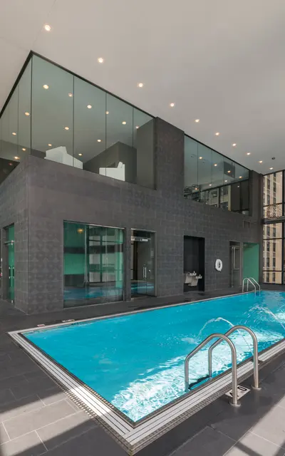 A modern indoor pool area with large windows, bright lighting, and sleek designs.