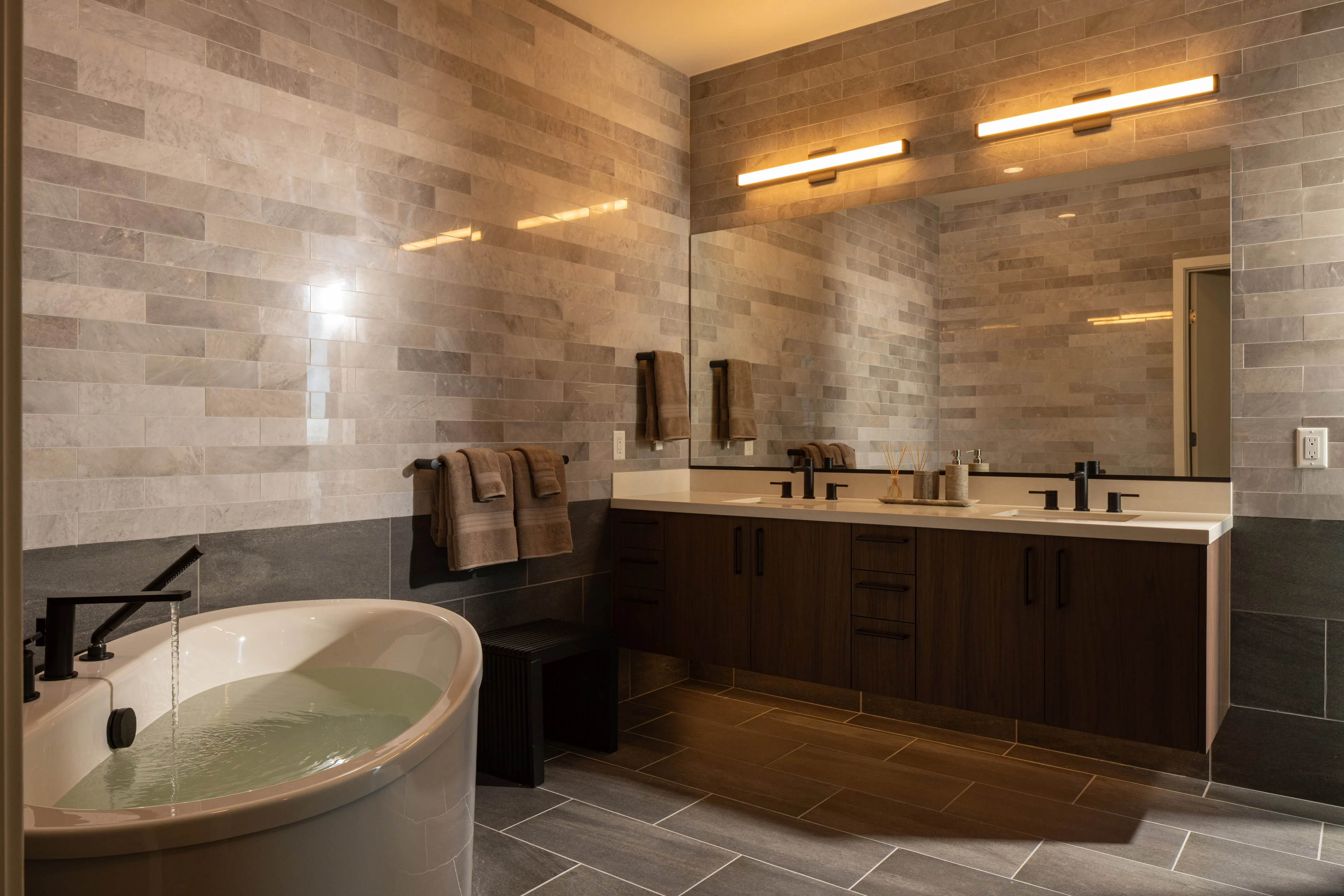 Stylish bathroom featuring a freestanding bathtub, dual sinks, and modern lighting.