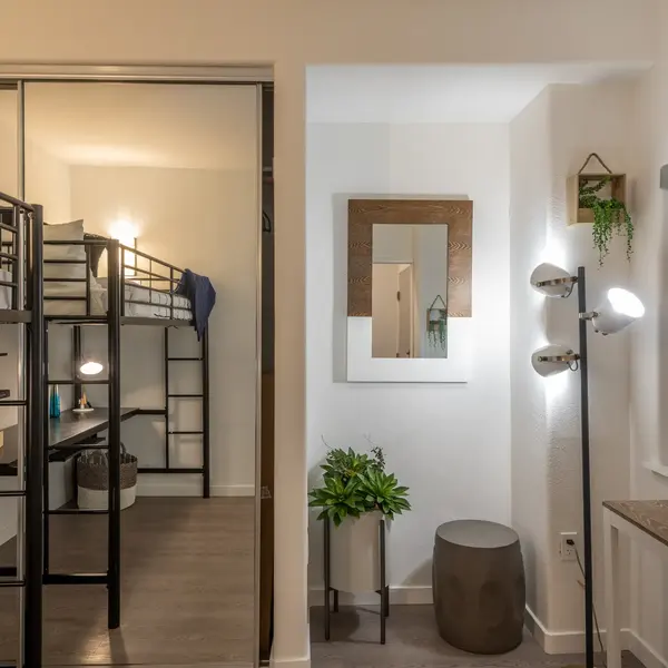 A modern bedroom featuring bunk beds with a mirror on one wall and modern lighting.