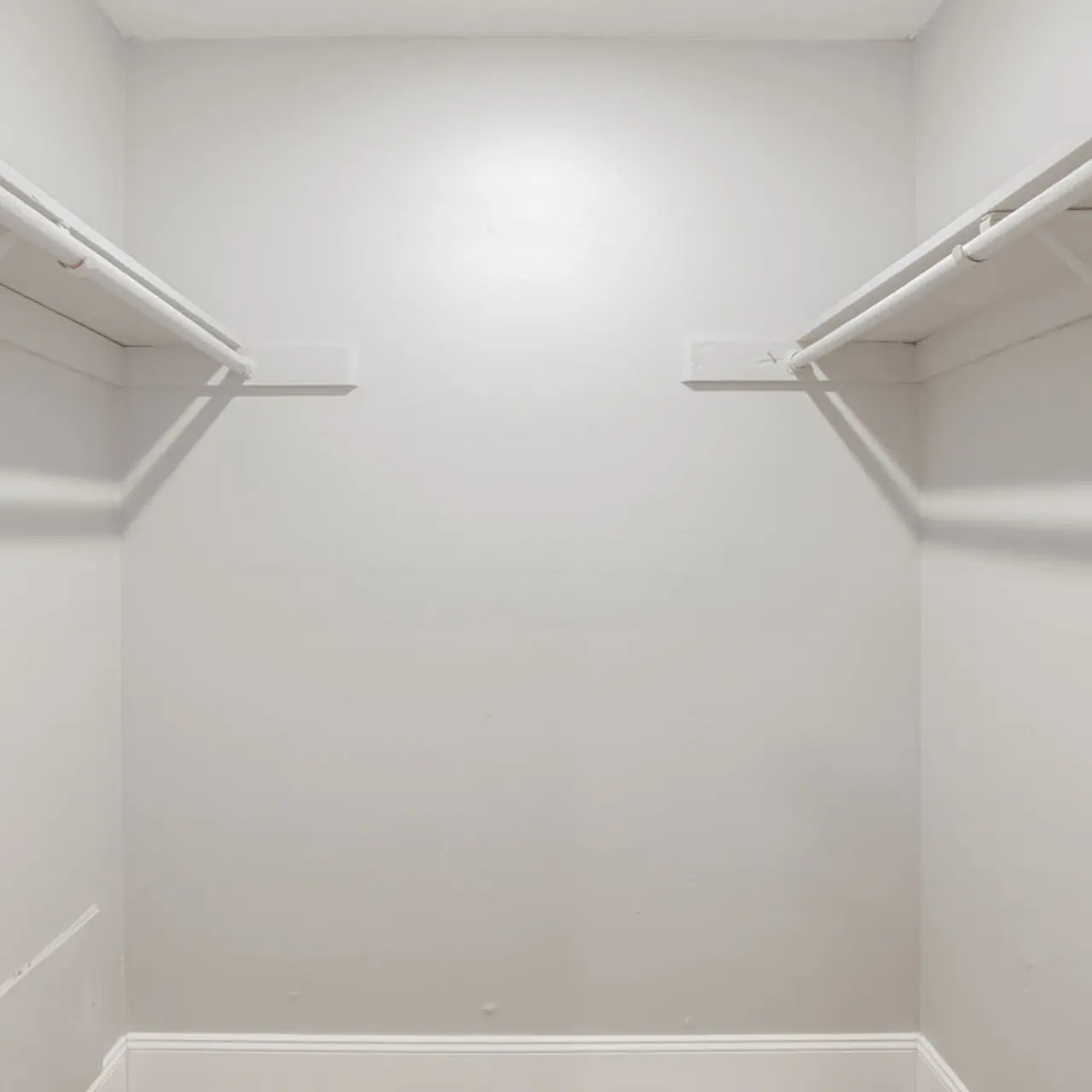 An empty closet with two shelves on either side against light gray walls.