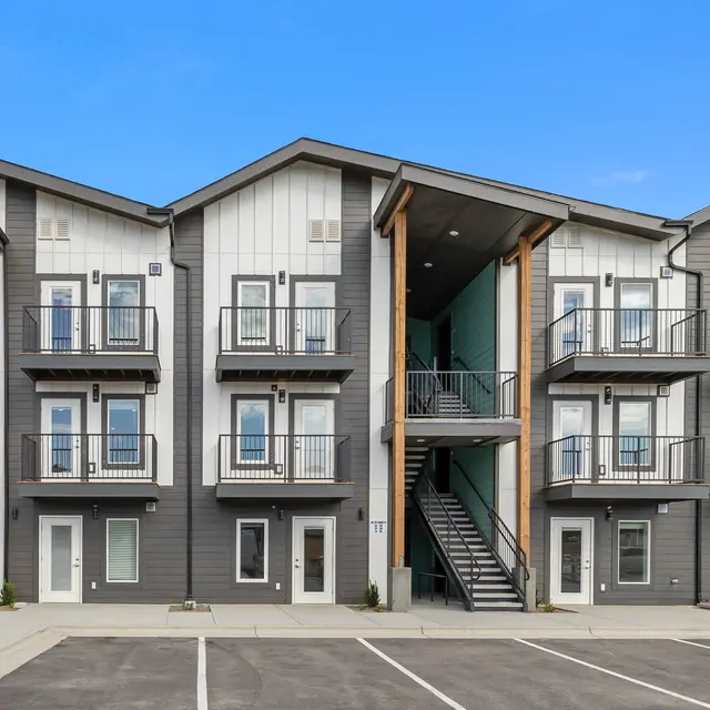 A modern apartment complex with multiple units featuring balconies, staircases, and a contemporary design.