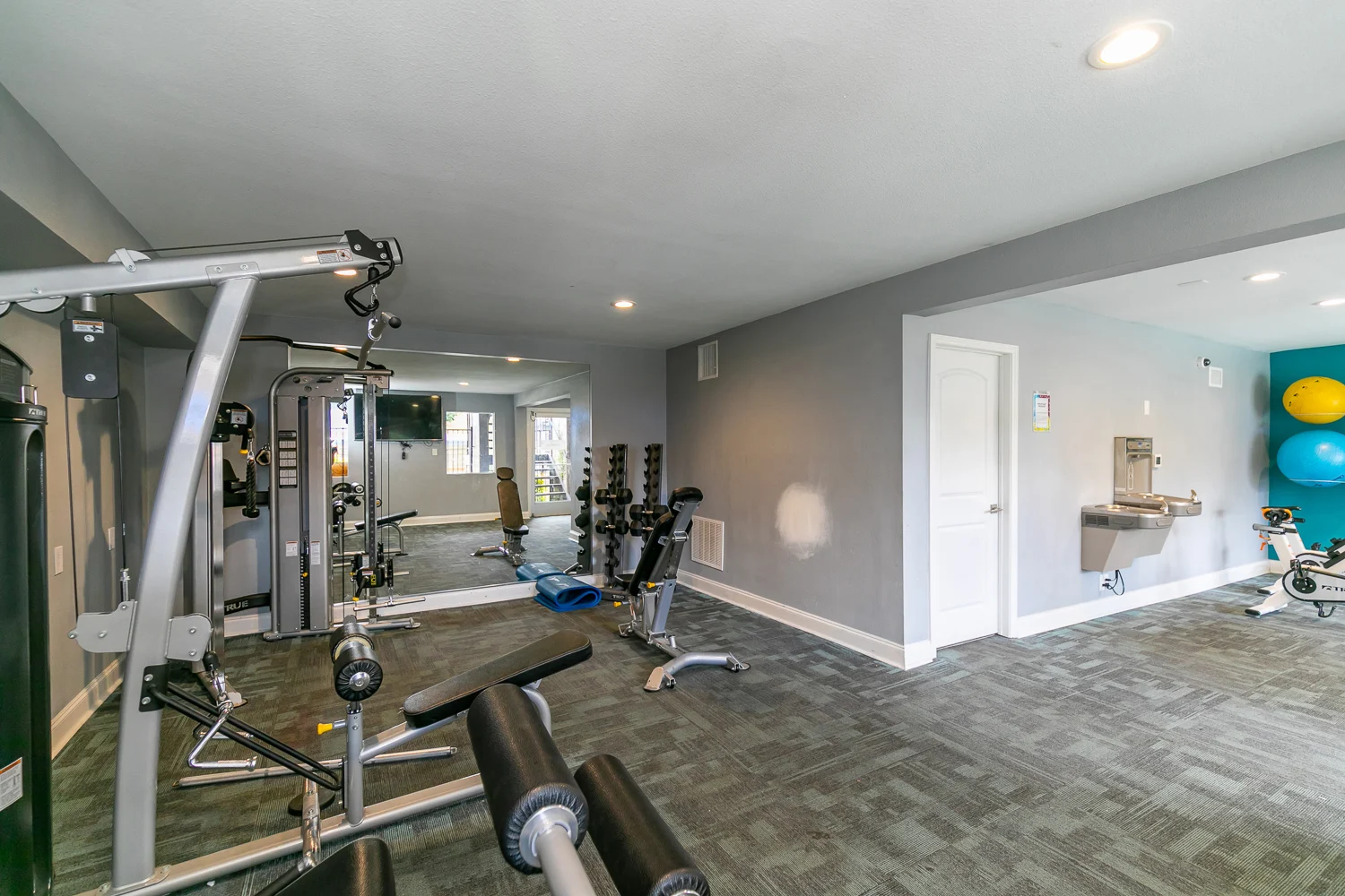 Modern Gym Interior Interior view of a gym featuring various workout equipment including weight machines, dumbbells, and exercise balls in a bright and modern space.