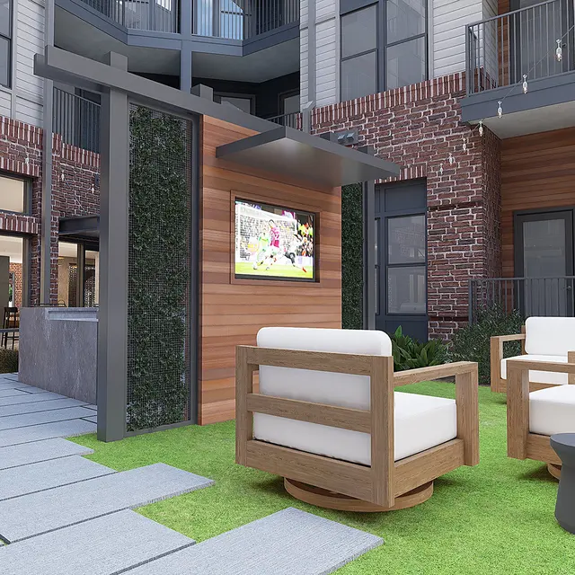 Outdoor lounge area featuring two wooden chairs, a small side table, and a television mounted on a wooden structure amidst a landscaped setting with grass and stone pathways.