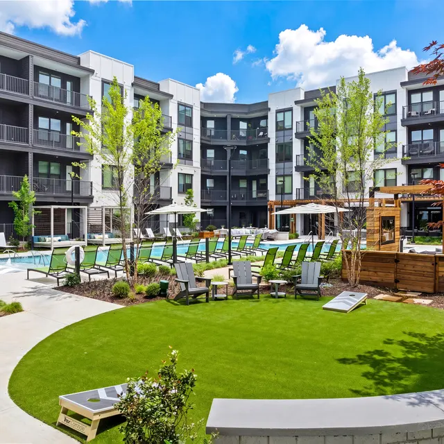 Modern Apartment Pool Area A modern apartment community pool area with lounge chairs, greenery, and an outdoor space.