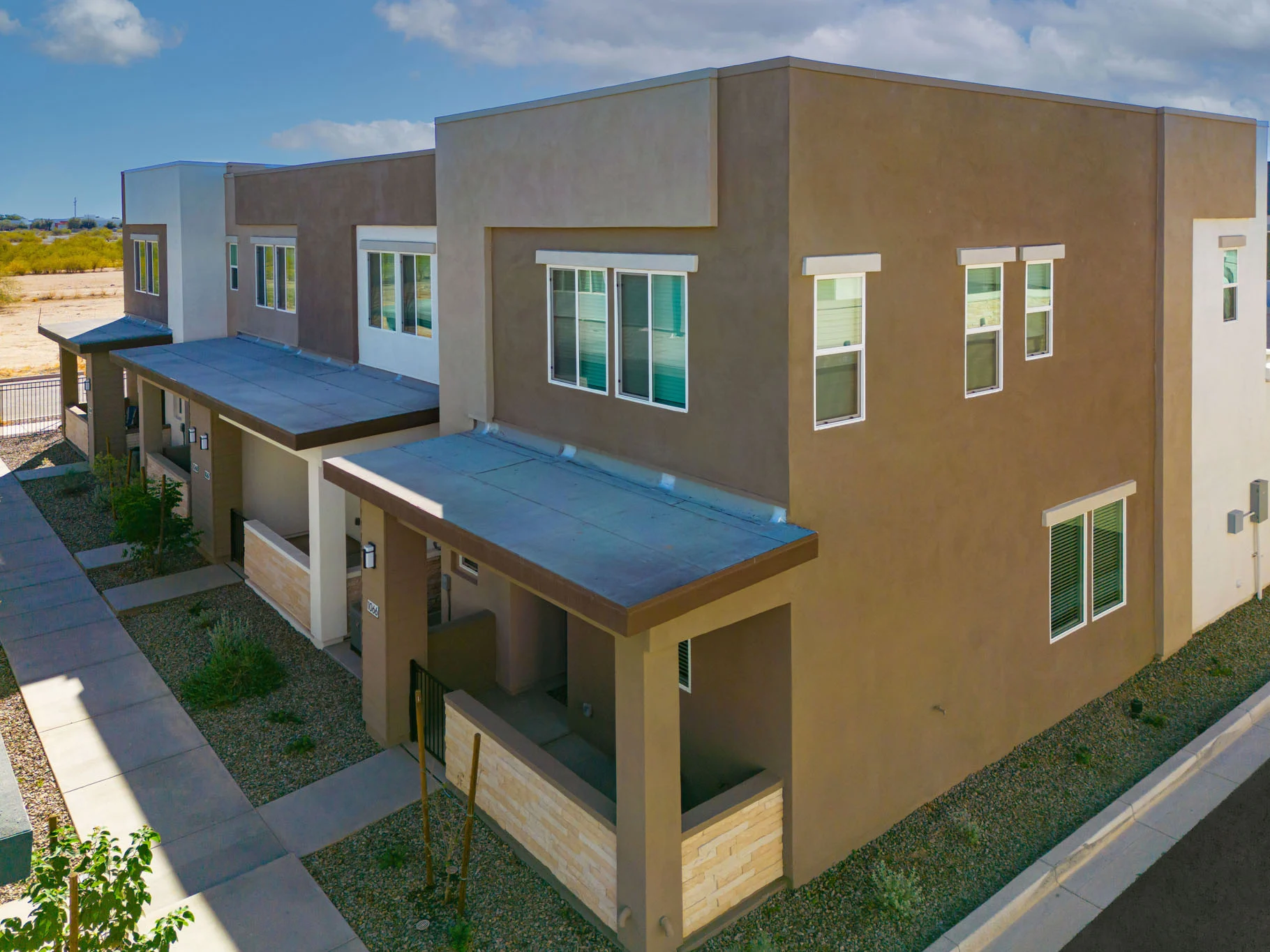 Modern Townhouses Aerial View Aerial view of modern townhouses with beige exteriors and multiple windows.