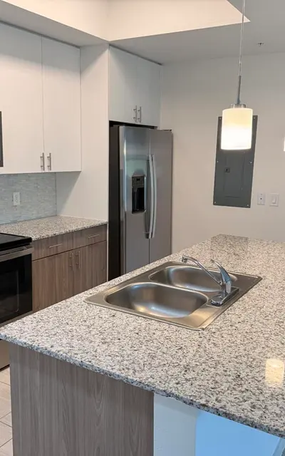 A modern kitchen with granite countertops, stainless steel appliances, and pendant lighting.