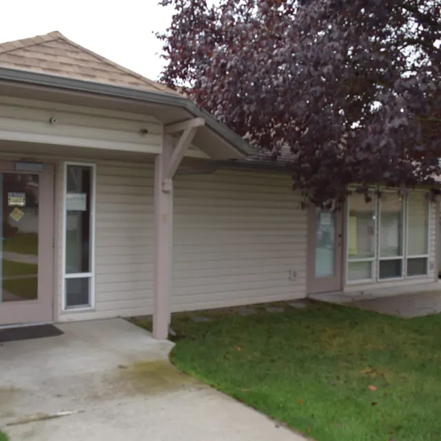 Building Entrance and Lawn External view of a single-story building with a porch and a well-manicured lawn.