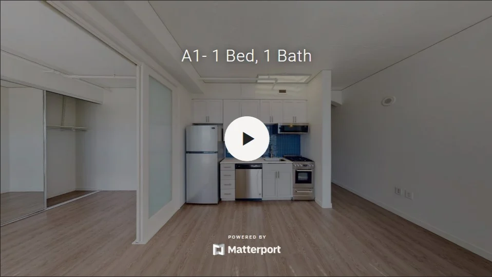 A modern one-bedroom, one-bath apartment interior showcasing a kitchen with appliances and an open living area.