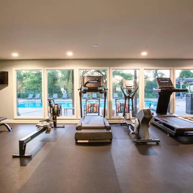 Modern Gym with Pool View View of a modern gym with exercise equipment facing large windows overlooking a swimming pool.