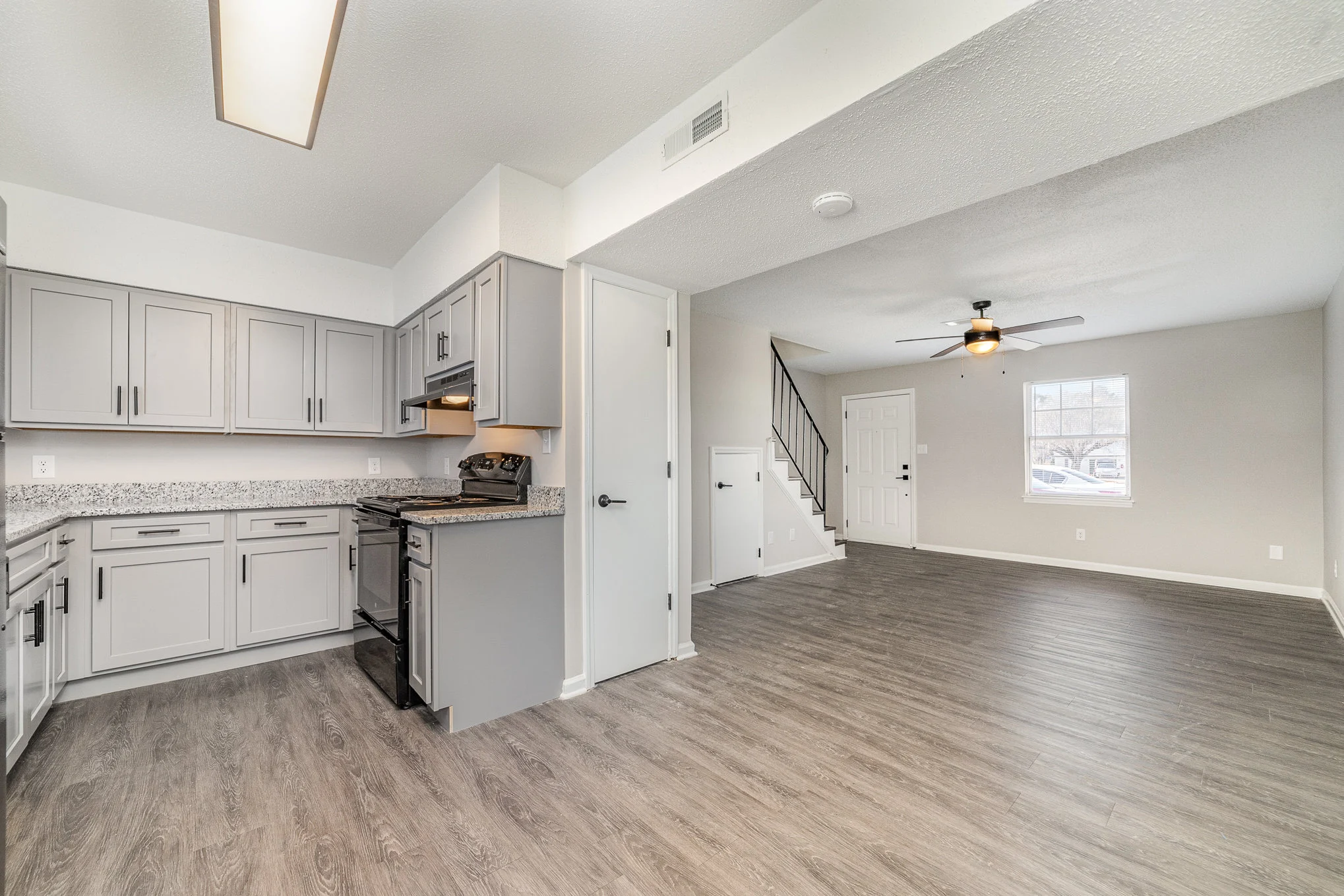 A modern kitchen and living area with light gray cabinets and a spacious floor layout.