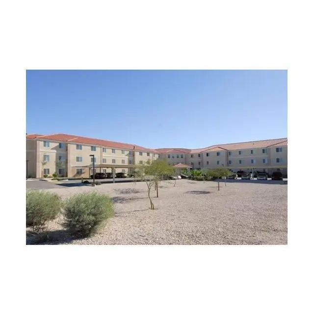 Hotel Exterior View Exterior view of a hotel building surrounded by gravel and sparse vegetation under a clear blue sky.