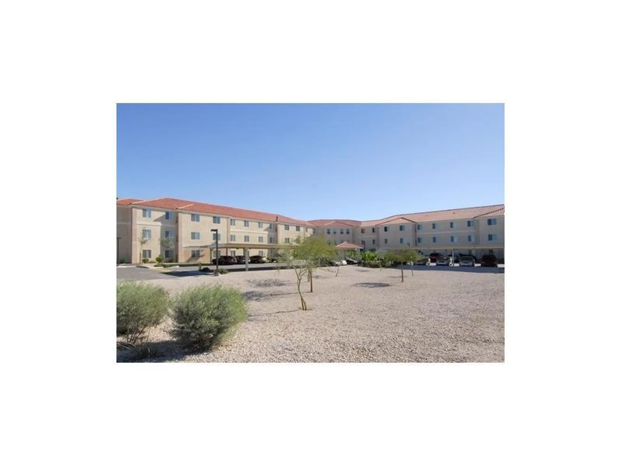 Apartment buildings around a gravel courtyard with a covered central feature.
