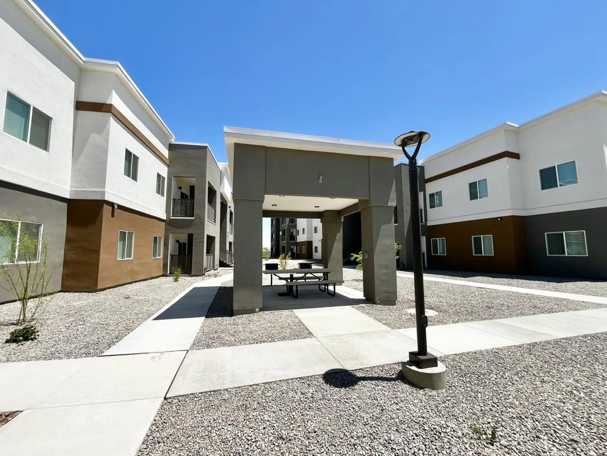 Covered picnic ramada in a courtyard between three-story buildings.