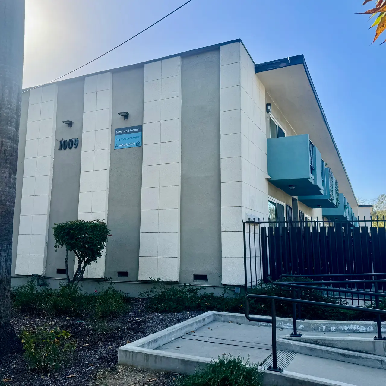Modern Building Exterior Exterior view of a modern building with three stories, featuring a blue and white color scheme and a palm tree in front.
