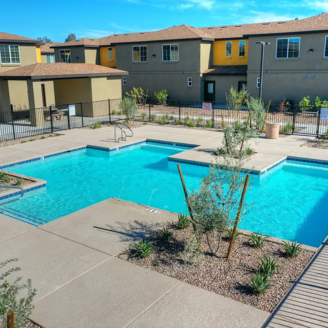 Community Pool Area A community swimming pool with landscaped areas and surrounding apartments in the background.