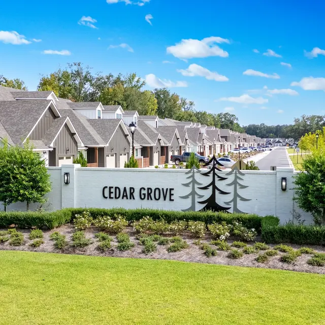 Cedar Grove Residential Community A residential community called Cedar Grove with multiple houses lined up, surrounded by green landscaping and trees under a clear blue sky.