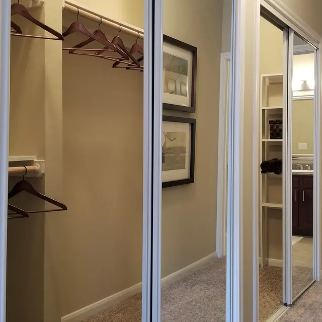 Interior view of a room showing a mirrored closet, a light switch on the wall, and doorways leading to other areas of the house.
