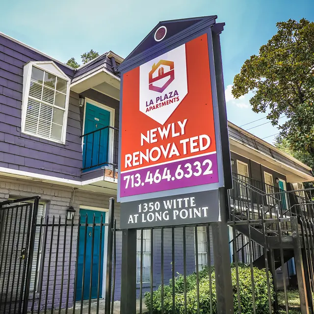 La Plaza Apartments Renovation Announcement A brightly colored sign in front of a building that reads 'La Plaza Apartments' and 'Newly Renovated' with a phone number, showcasing the apartment complex.