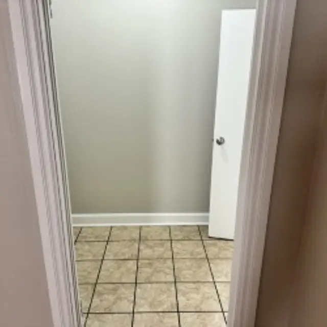 View into an empty room with tiled flooring and a white door on the right.