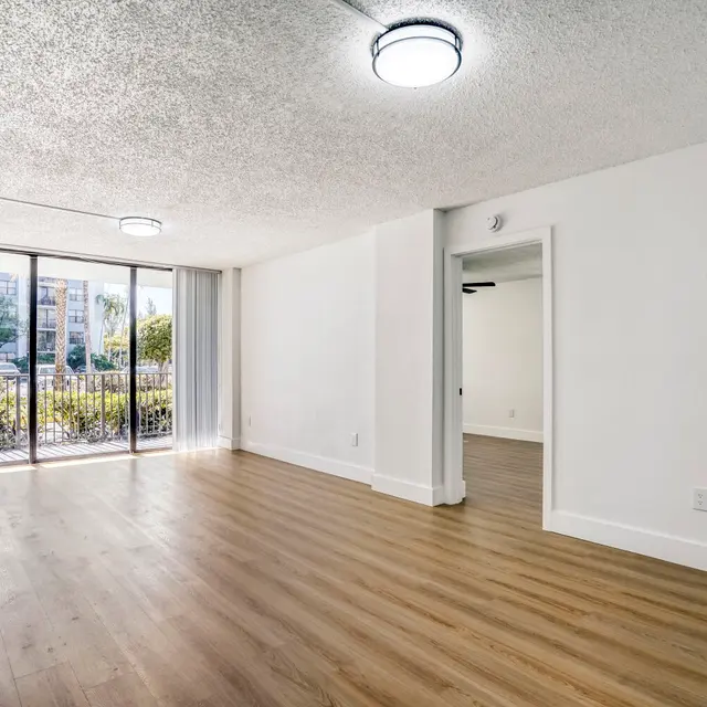 Spacious Apartment Interior An empty apartment interior with wooden flooring, large windows, and bright lighting.