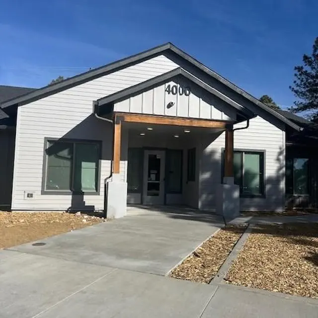 Contemporary Building Entrance A modern one-story building with a sloped roof and wooden accents at the entrance. The building features large windows and a paved pathway.