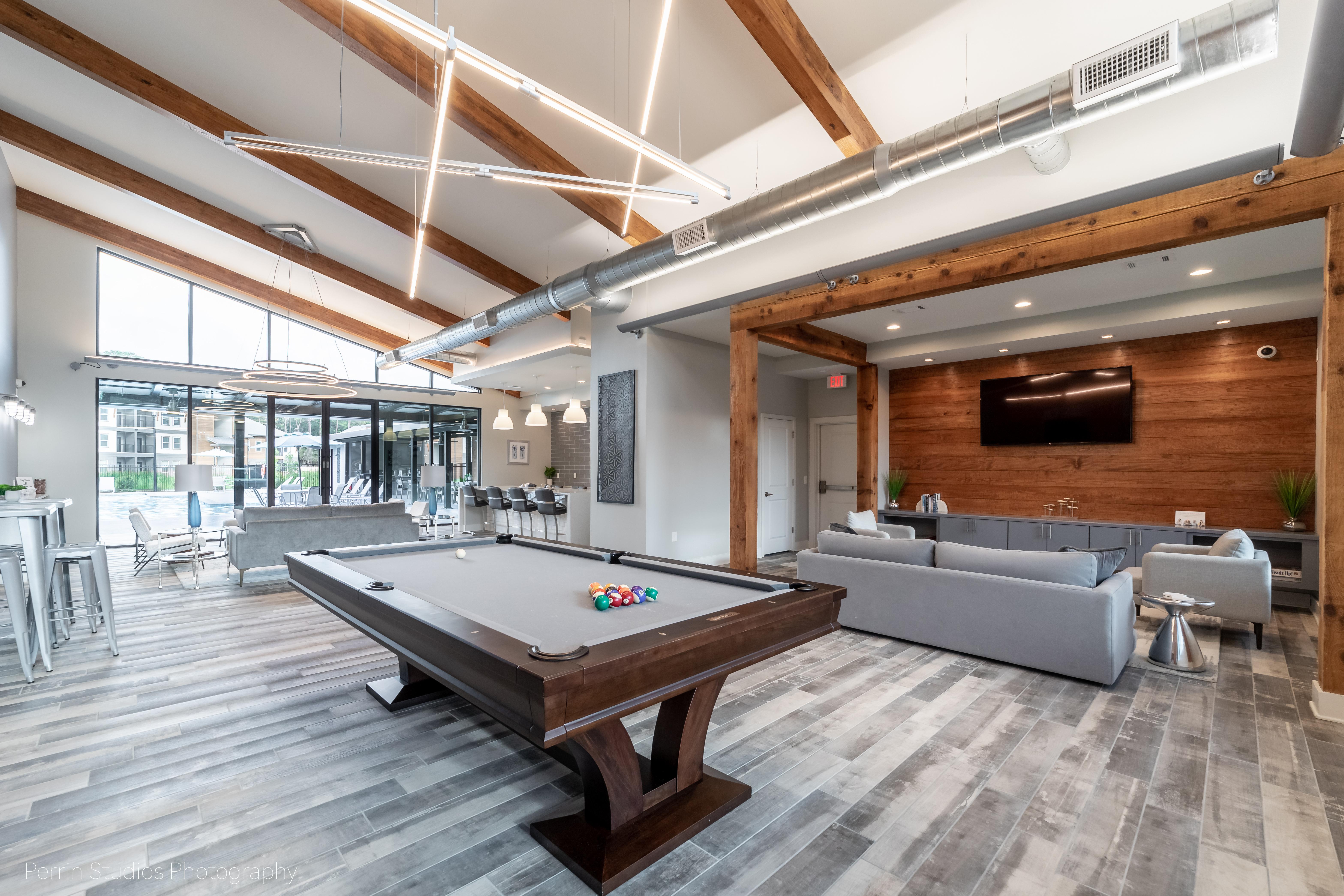 Modern interior of a lounge area with pool table, stylish furniture, and large windows.