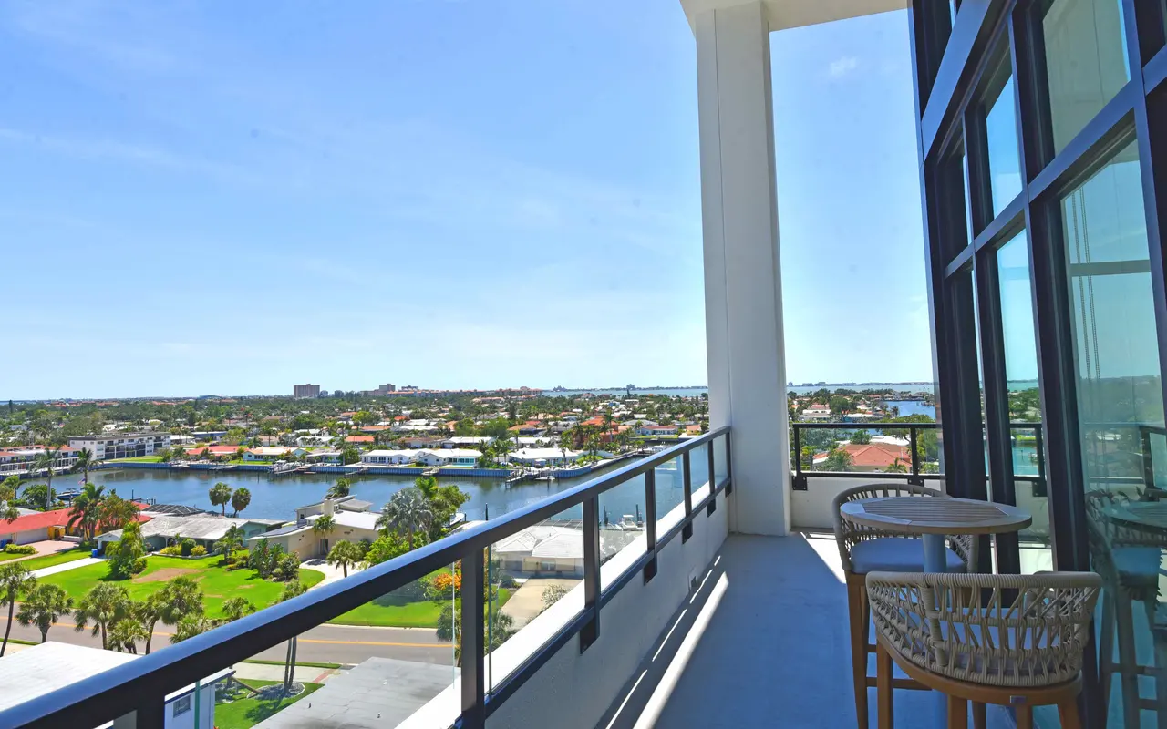 A scenic view from a balcony overlooking a marina and residential area, featuring blue skies and a peaceful atmosphere.