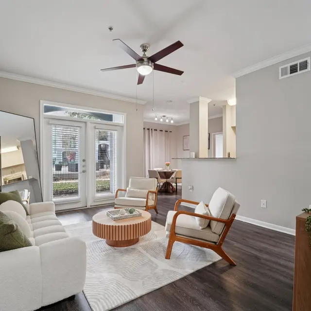 Cozy Modern Living Room A cozy modern living room with white sofas, a round wooden coffee table, and large windows letting in natural light.