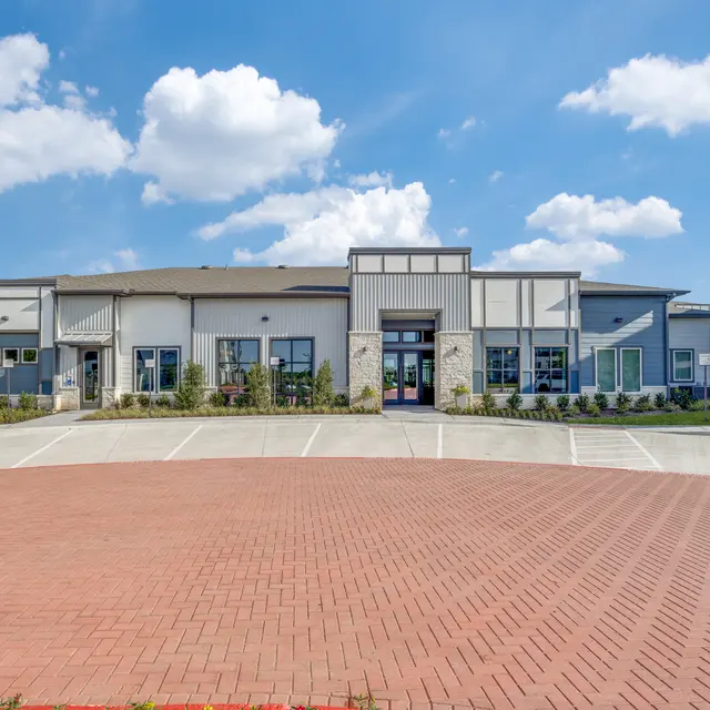 Exterior view of a modern apartment complex with blue skies and clouds