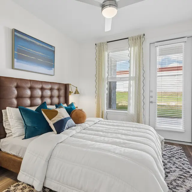 Modern Bedroom Design A modern bedroom featuring a brown tufted headboard bed with white linens and decorative pillows, two windows with white curtains, and a stylish nightstand with a lamp and decorative items.