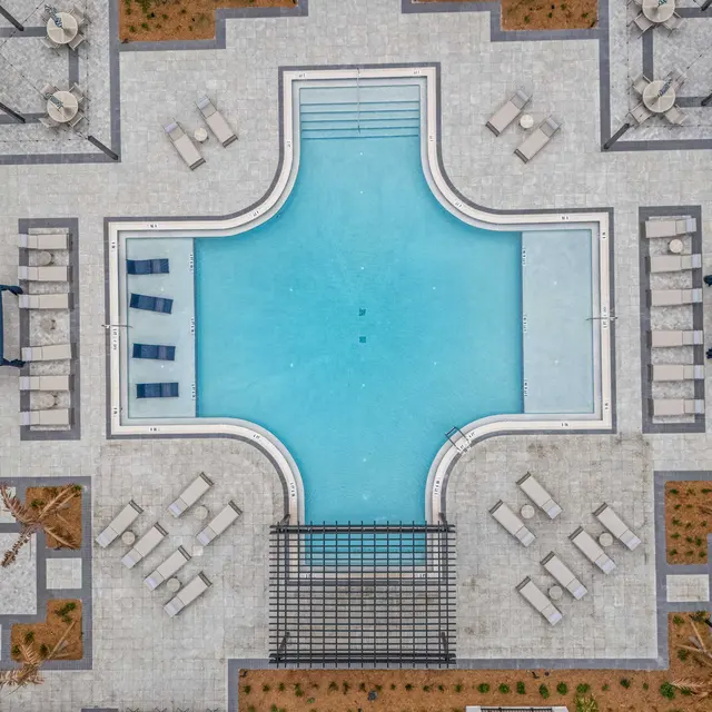 Modern Aerial View of a Pool Area Aerial view of a modern pool area surrounded by lounge chairs and small cabanas, featuring geometric landscaping.