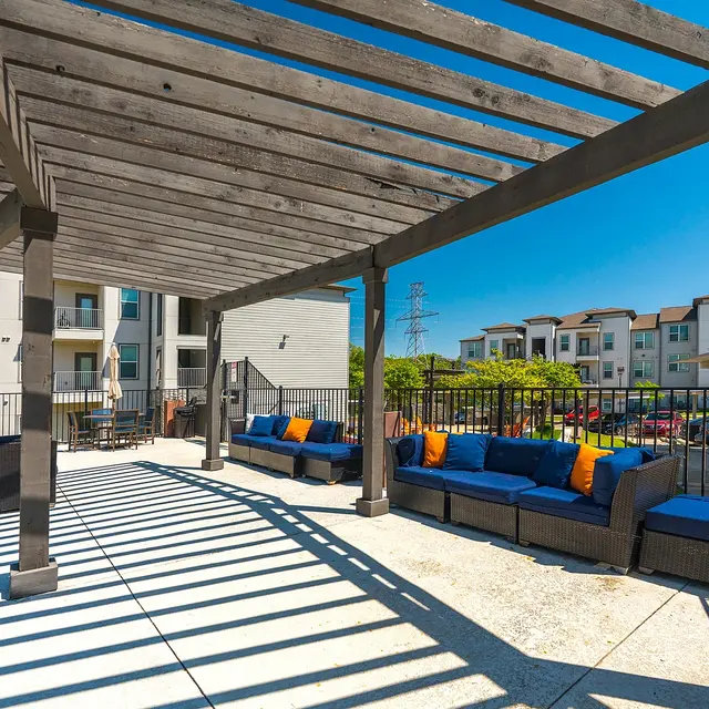 Outdoor lounge area with a wooden pergola and blue couches.
