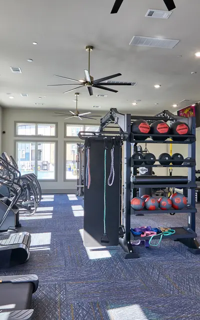 A spacious modern gym interior featuring exercise equipment, large windows, and bright lighting.