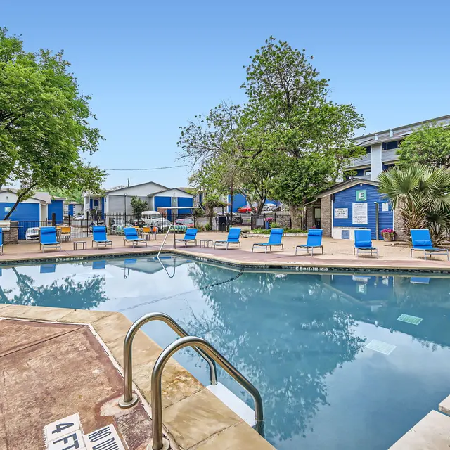A swimming pool surrounded by landscaped greenery and lounge chairs in an outdoor setting.