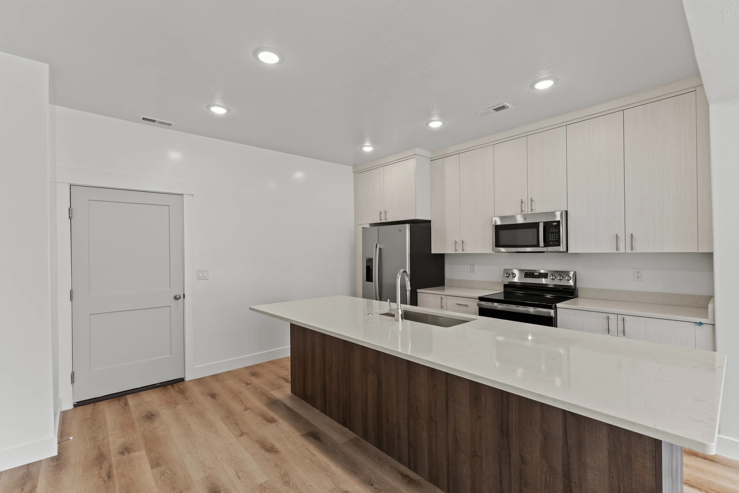 Modern Kitchen with Island A modern kitchen featuring a large island with a sink, stainless steel appliances, and a mixture of light and dark cabinetry.