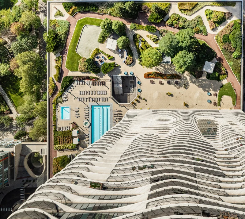 Aerial view of a swimming pool and landscaped area with greenery and seating.