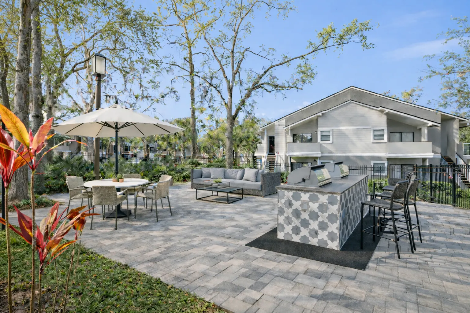 Outdoor Community Space with BBQ An outdoor community space featuring a barbecue area, seating, and dining tables under the shade of trees.