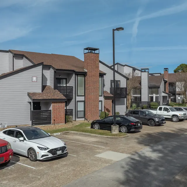 View of a multistory apartment complex with parked cars in the foreground.