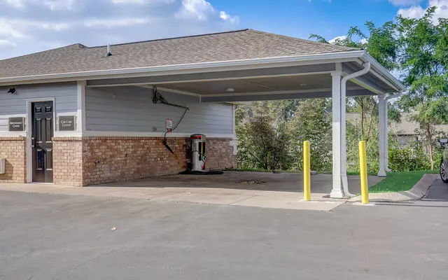 A covered parking area with a brick wall on one side and a car charging station visible.